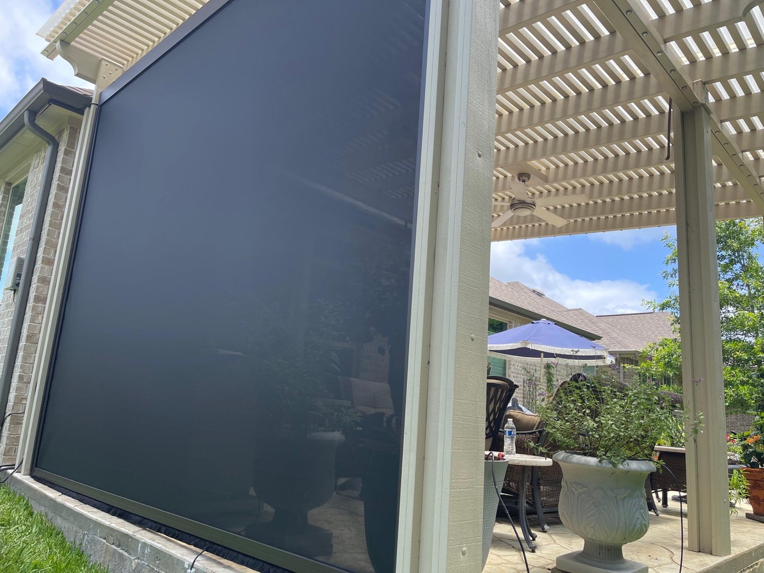 Exterior solar screen shade installed on a covered patio